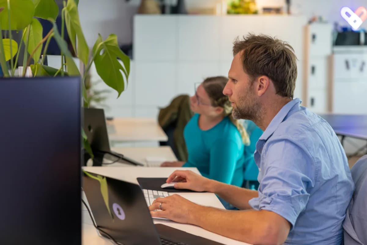 Twee collega's werken samen achter een laptop